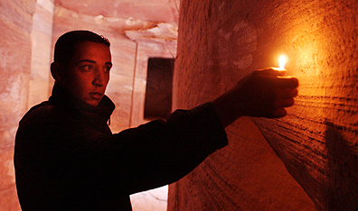 A tourist examines carvings on a wall inside a tomb at Petra. Photo Chris Hondros/Getty Images.