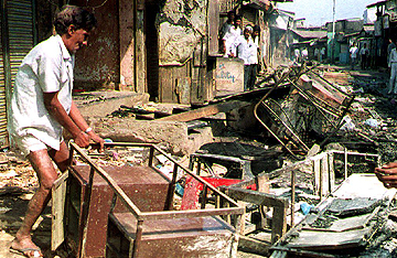 A shopkeeper clears debris after a Bombay riot in January, 1993. Photo Douglas E. Curran/AFP/Getty Images.
