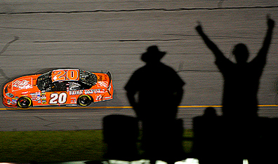 Spectators watch driver Tony Stewart in action during the NASCAR Nextel Cup Series Pepsi 400 in Daytona Beach, Florida. Photo Ronald Martinez/Getty Images.
